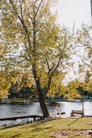 Scenic lakeside wedding venue with autumn trees and wooden dock during golden hour.