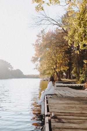 Romantic lakeside dock scene with autumn trees and golden sunlight.