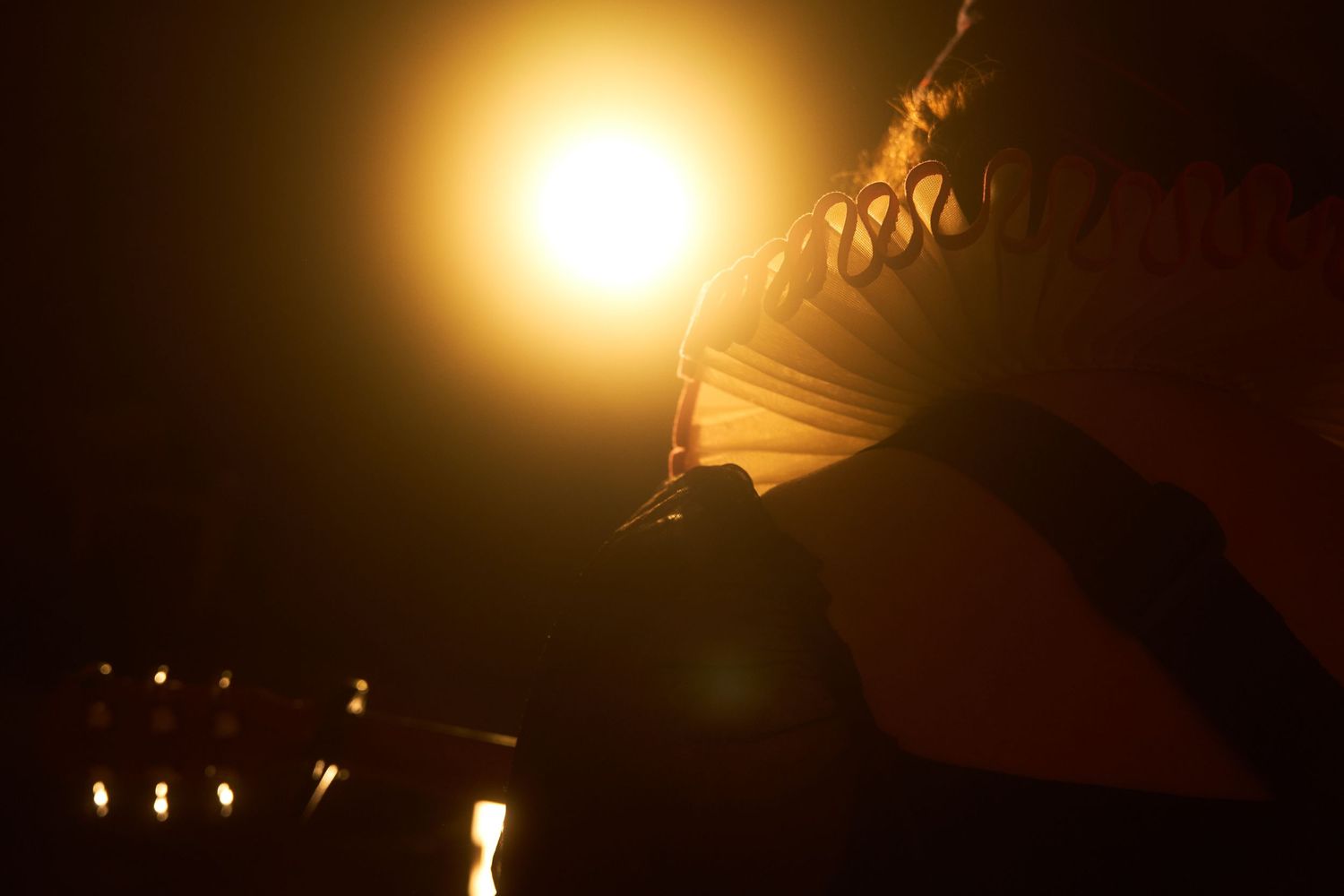 Figure découpée contre une source de lumière chaude et lumineuse dans une atmosphère sombre.
