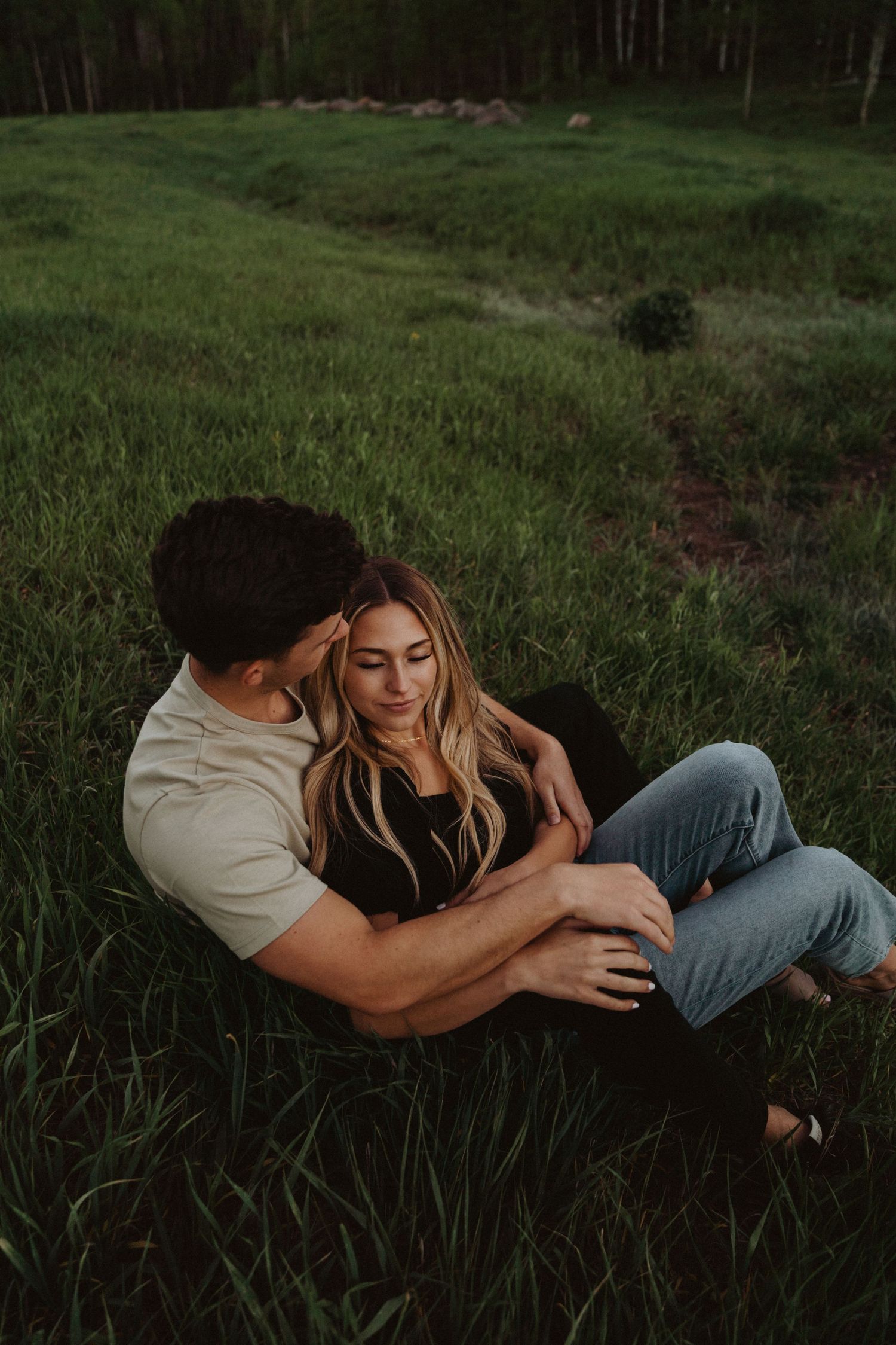 Intimate couple portrait session in tall grass during moody sunset lighting.