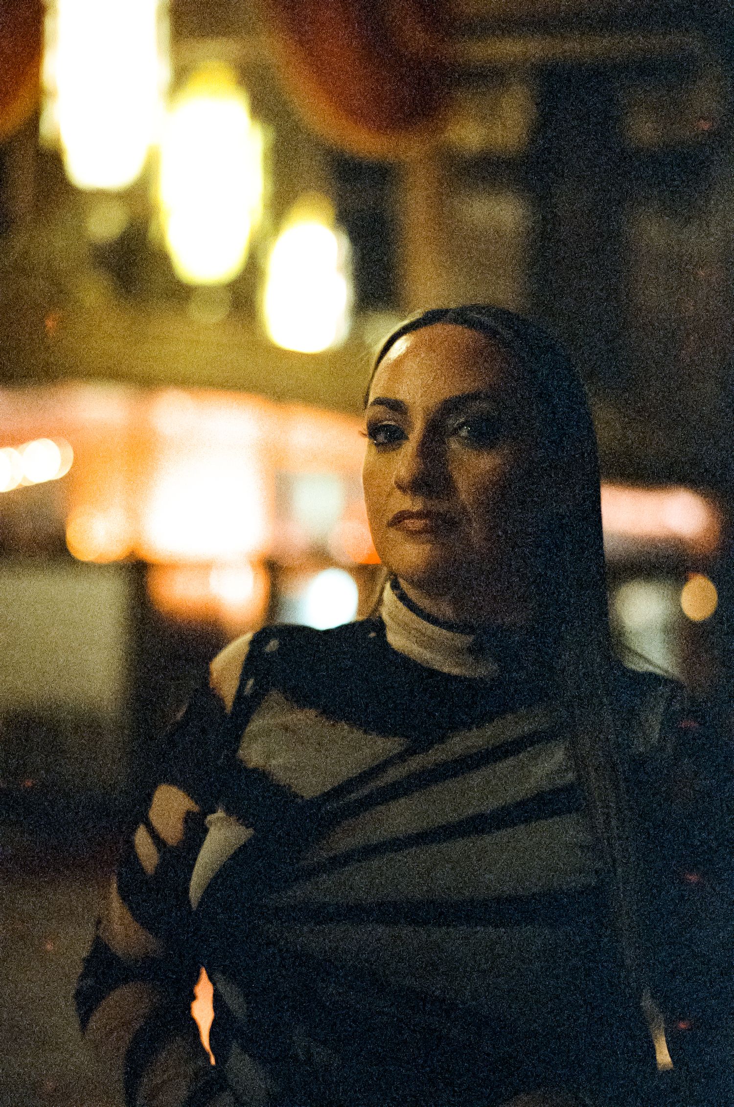 Moody nighttime portrait with blurred lights and urban atmosphere.