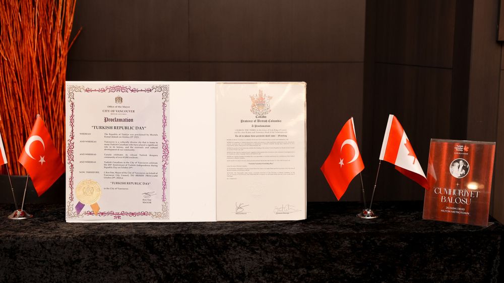 Official documents and small flags of Turkey and Canada displayed on a black table.