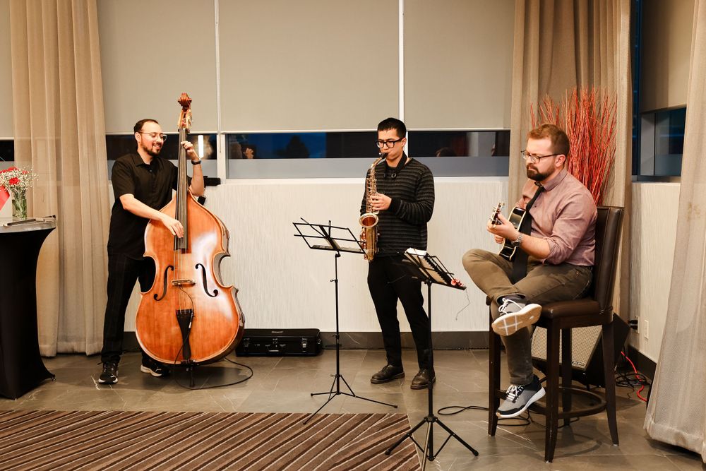 Jazz trio performing with double bass, clarinet and guitar at an indoor event.