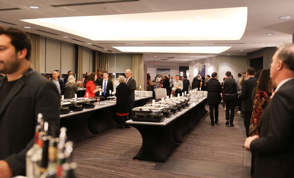 Formal event setup with long buffet tables and guests mingling in a conference room.