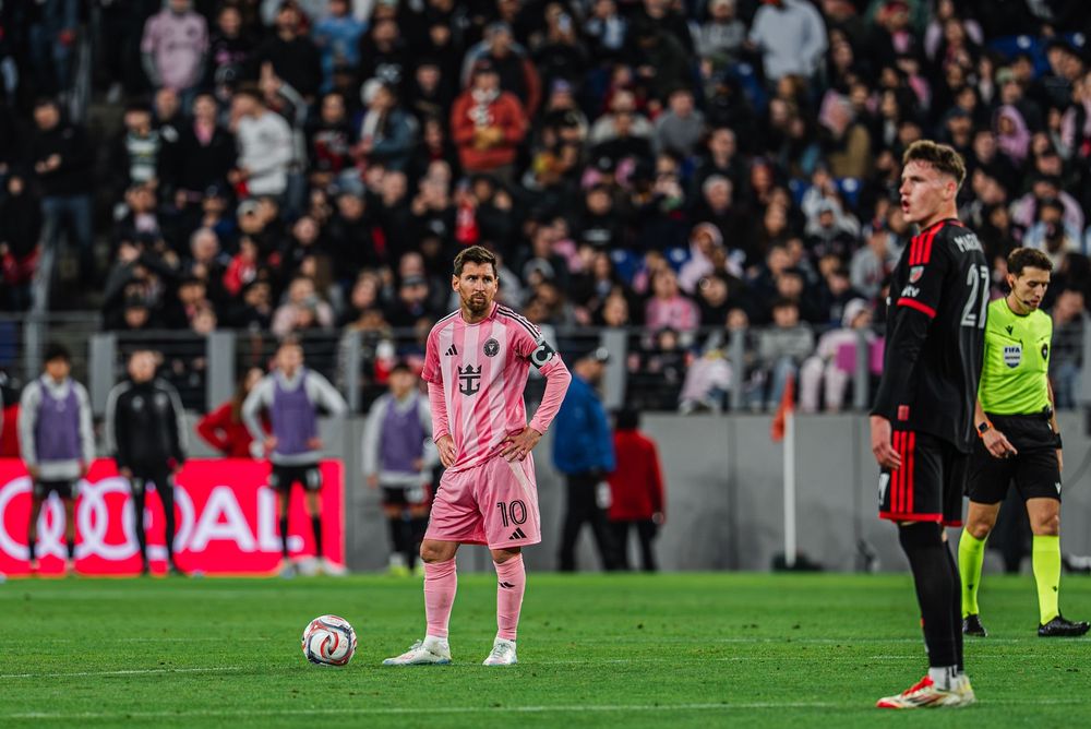 Soccer players in pink and black uniforms compete during a professional match at a crowded stadium.