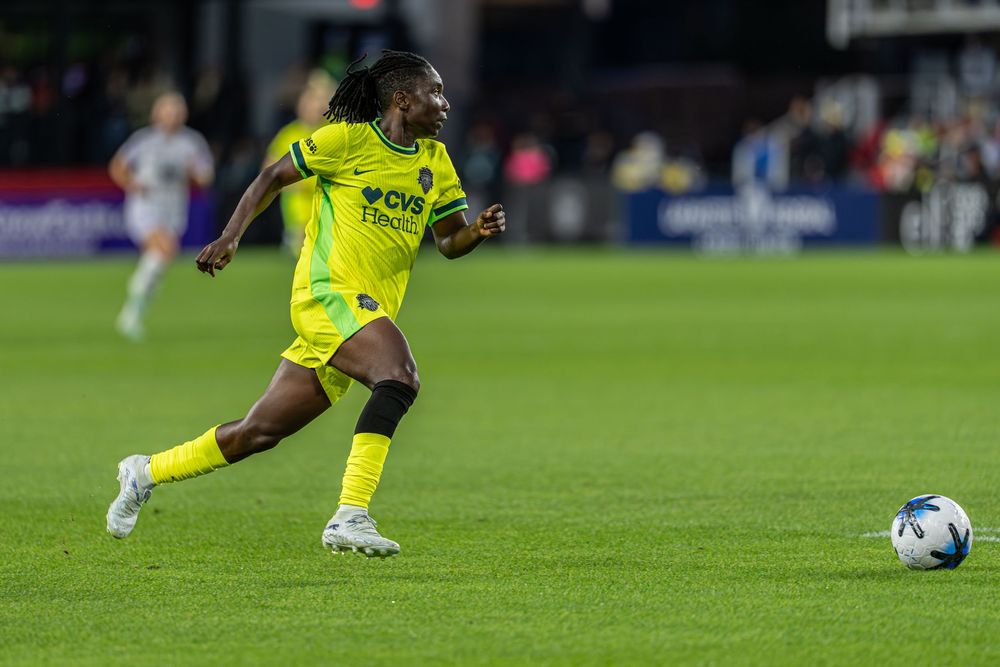 Soccer player in yellow CVS jersey dribbles ball on field during night match.