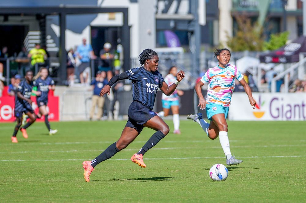 Soccer players compete for the ball during an intense match on a sunny day at a professional stadium.