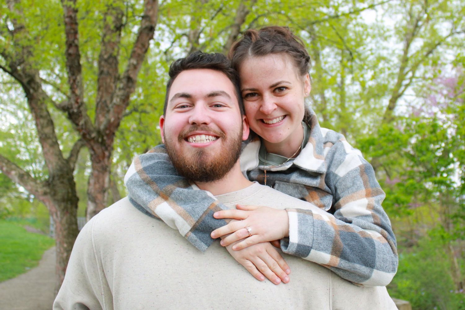a couple smiling in front of bright green trees