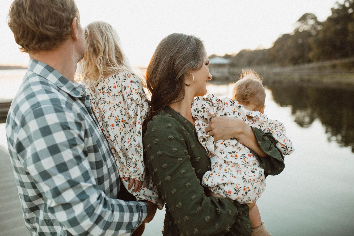Photo by B.Logsdon of Bluffton, SC of a family standing together by a serene lake at sunset, with trees reflecting in the calm water.