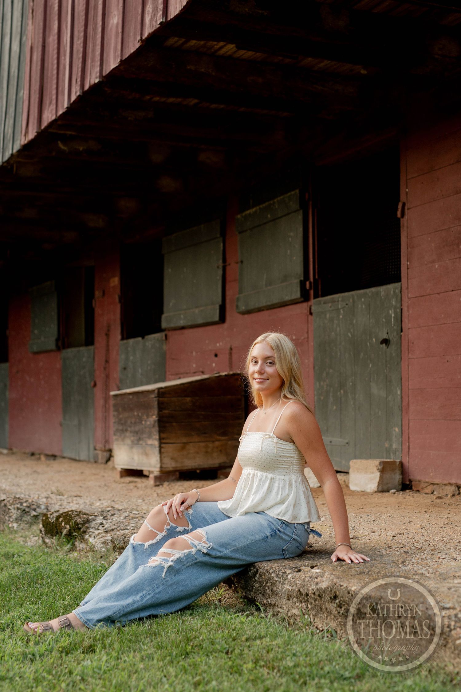 Casual portrait session by weathered red barn with distressed wood details.