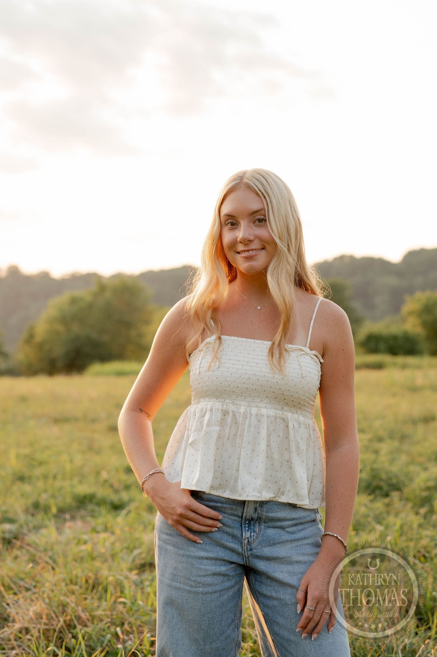 Sunset portrait in golden field with rolling hills in background.
