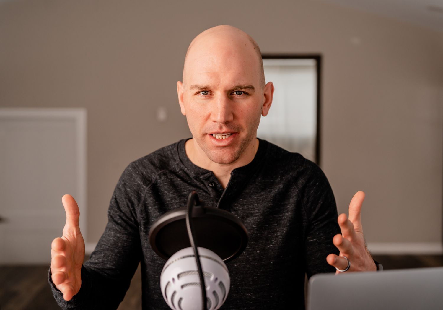 A person in a dark sweater gestures while speaking during a conversation in an indoor setting.