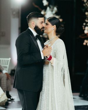 A couple shares an intimate dance moment at their wedding, with the bride wearing a stunning white beaded gown.
