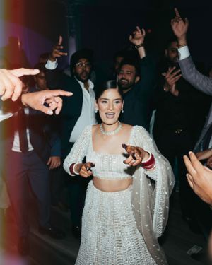 People dancing and celebrating at a party with someone in a sparkly white two-piece dress in the center.