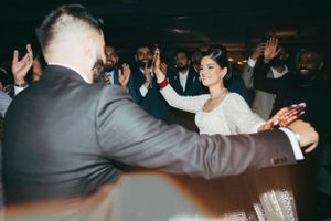 Lively dance party scene at a wedding reception with people in formal wear dancing and celebrating.
