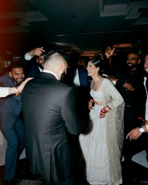 Wedding party dancing and celebrating on a dimly lit dance floor with festive energy.