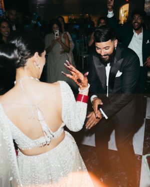 Couple in formalwear dance together at an evening celebration, with the bride wearing a sparkly white dress.