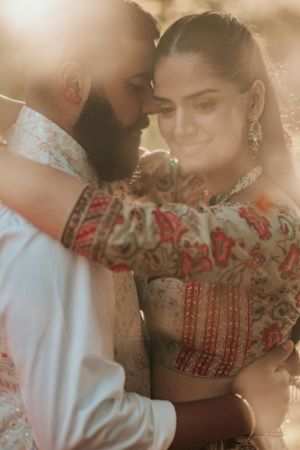 Romantic couple in traditional Indian attire sharing an intimate moment in warm golden sunlight.