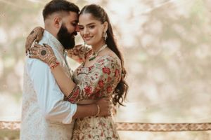 A romantic couple in traditional Indian attire embraces while posing during an outdoor photoshoot.
