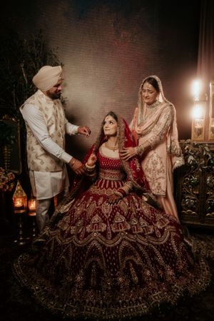 A traditional Indian wedding scene captured in warm lighting with elegant attire including a deep red bridal lehenga.