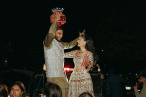 A couple in traditional ethnic attire celebrates during a dance or celebration event at night.
