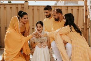 A joyful celebration with people in yellow traditional Indian attire during a sunny outdoor ceremony.