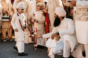 Family members dressed in traditional cream colored Indian wedding attire gathered during a ceremony.