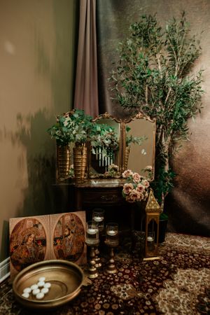 Ornate traditional Hindu altar display with greenery, candles, and decorative elements in a moody setting.