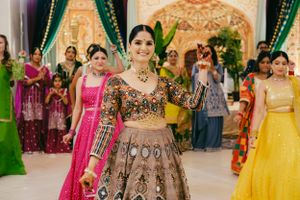 Traditional lehenga in detailed embroidery stands out among colorful wedding guests in an ornate venue.