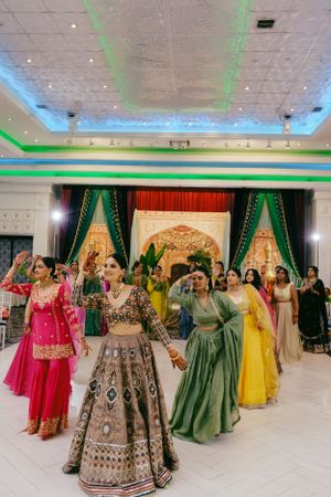 Festive dance celebration at an Indian wedding reception with guests in colorful traditional lehengas and gowns.
