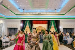 Traditional Indian wedding reception with dancers in colorful lehengas performing in a decorated banquet hall.