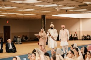 Traditional Indian wedding ceremony taking place in a modern banquet hall with elegant decor and gathered guests.