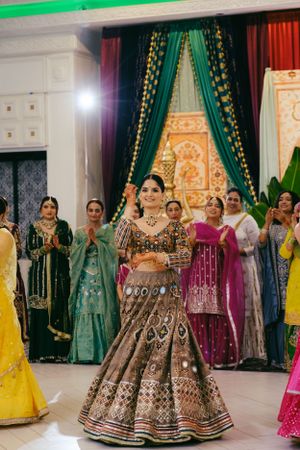 A dance celebration at an Indian wedding with people in colorful traditional lehengas and formal attire.