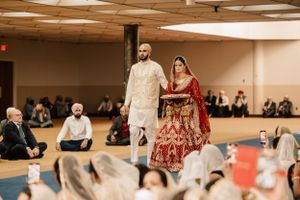 Traditional Indian wedding ceremony in a banquet hall with guests seated on the floor watching the proceedings.