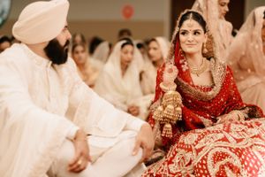 A traditional Sikh wedding ceremony with the bride in red attire and guests wearing white during the ritual.
