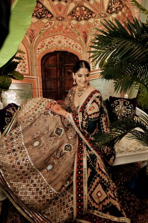 Traditional embellished lehenga in brown and gold with intricate embroidery photographed against ornate architectural backdrop.