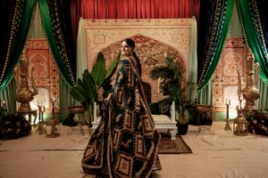 Ornate wedding venue with luxurious green drapes, Eastern-inspired decor, and traditional dress on display.