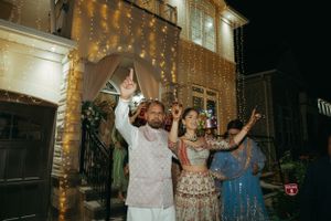 A festive celebration at night with people dancing under decorative string lights outside an illuminated building.