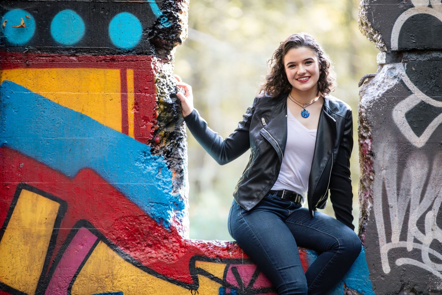 A person in casual wear sits alongside vibrant street art murals with colorful geometric shapes and designs.