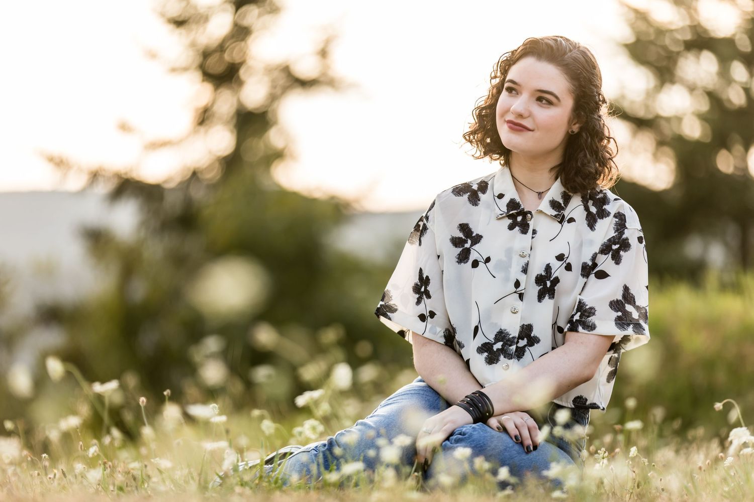 A retro-styled portrait in a wildflower meadow at sunset featuring a white and black floral print dress.