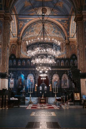 Interior of an ornate Orthodox church with grand chandeliers and decorated arches and frescoes.
