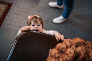 Small child peeking over the edge of a church pew during a service.