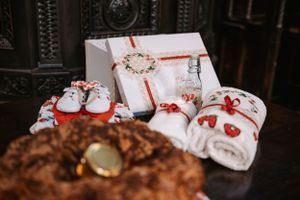 Baptism gifts including white box, shoes, and towel arranged on dark wooden surface.