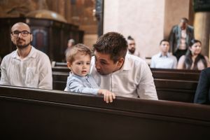 Attendees gather inside an Orthodox church during a religious ceremony with traditional decorations.