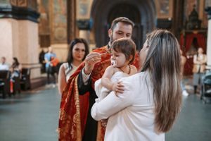 Emotional baptism ceremony captured in a traditional church with ornate decorations and warm lighting.