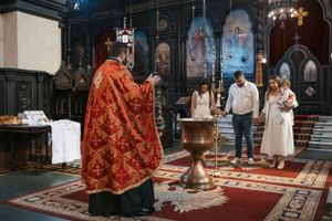 Religious ceremony in progress on red carpet inside ornate church interior.