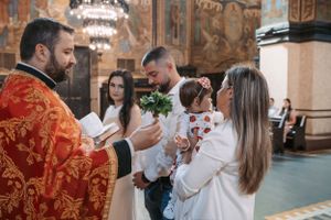 Traditional church ceremony with participants in white attire against decorative backdrop.