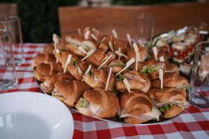 Platter of mini sandwiches served on a red and white checkered tablecloth.