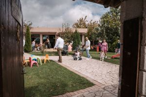 Outdoor party setting with guests mingling on a paved patio surrounded by greenery.