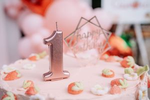 Pink birthday cake decorated with strawberries and silver number one candle.